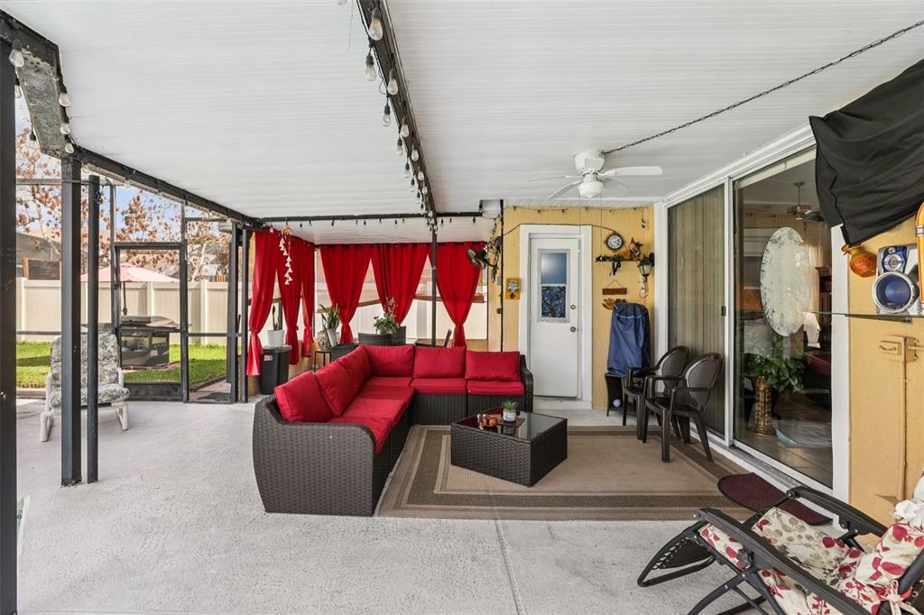 A covered patio features a red sectional sofa, a coffee table, and red curtains — 3521 MOLONA DRIVE, ORLANDO, FL