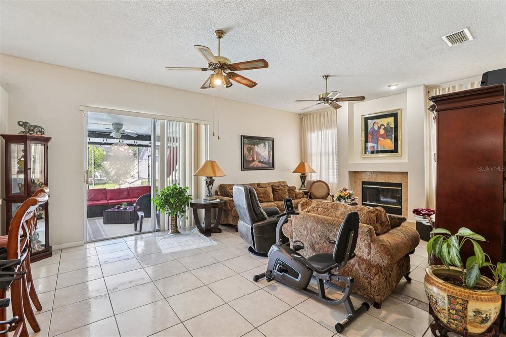 A living room features tile floors, a fireplace, two ceiling fans, and a sliding glass door — 3521 MOLONA DRIVE, ORLANDO, FL