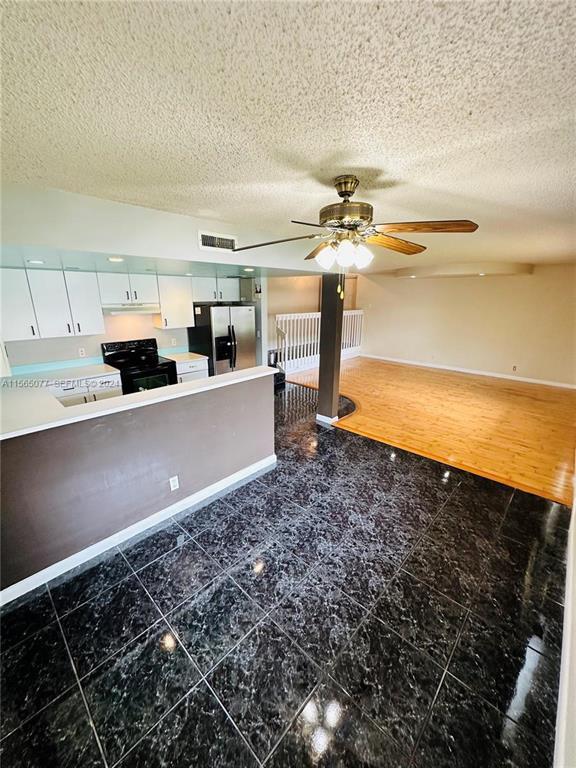 An open-concept kitchen with dark tile floors transitions into a living area with wood flooring — 4730 SW 62nd Way # 104, Davie FL 33314, DAVIE, FL