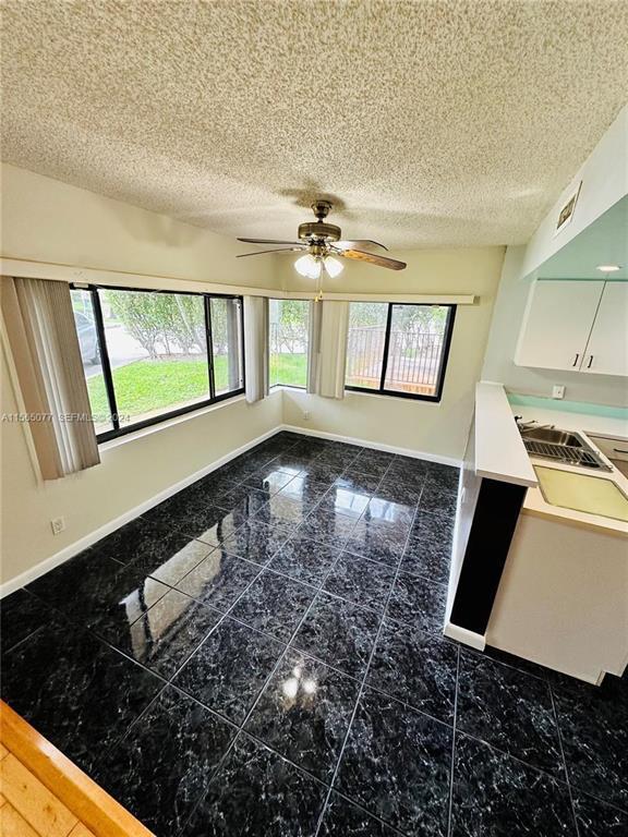 A dining area features dark marble-patterned tile floors, a ceiling fan, and large corner windows — 4730 SW 62nd Way # 104, Davie FL 33314, DAVIE, FL