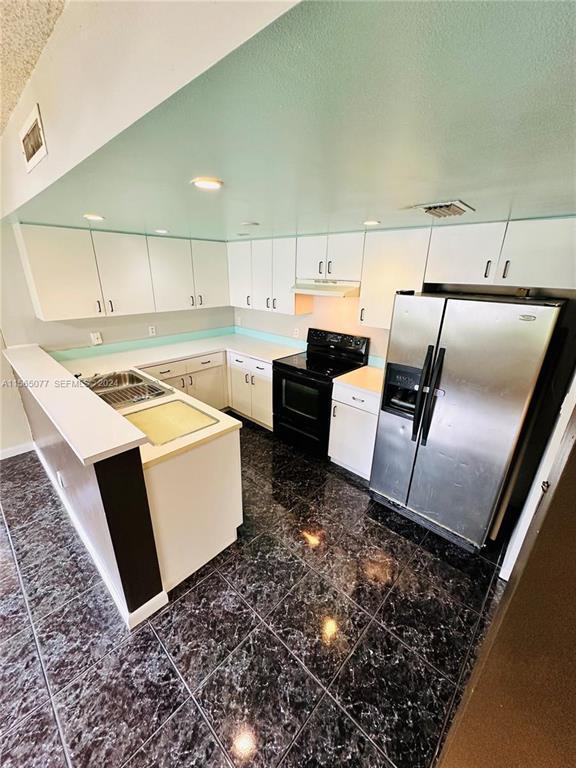 A kitchen features white cabinets, stainless steel appliances, and dark marble-patterned tile flooring — 4730 SW 62nd Way # 104, Davie FL 33314, DAVIE, FL