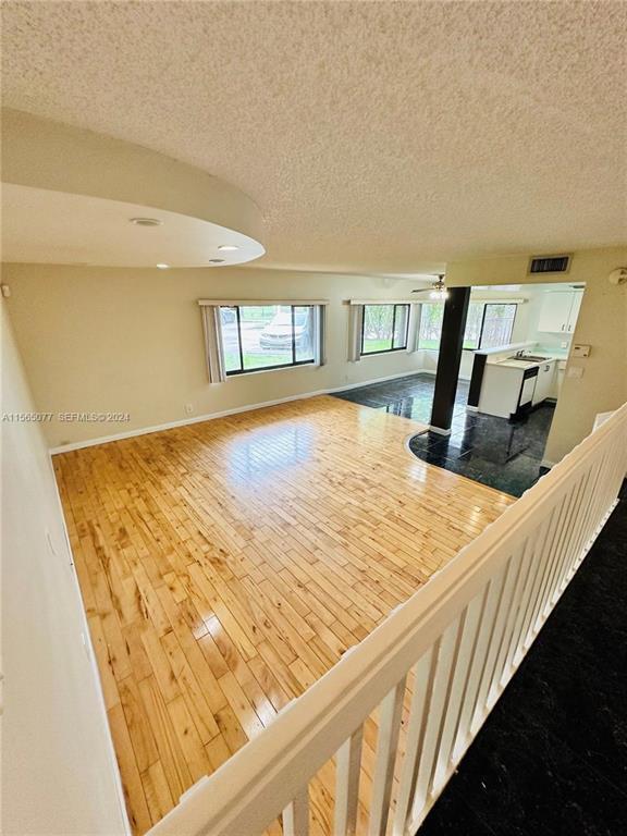 An elevated view of a living room with hardwood floors and an adjacent tiled kitchen — 4730 SW 62nd Way # 104, Davie FL 33314, DAVIE, FL