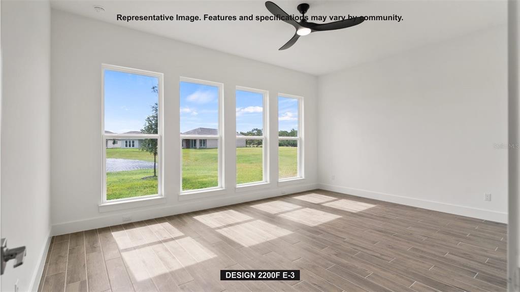 An empty room features wood-look tile flooring, a ceiling fan, and four large windows — 7910 BON AIR WAY, PARRISH, FL
