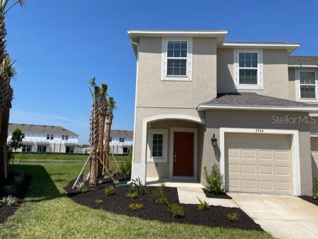 A two-story tan stucco house features a front-facing garage and a red entry door — 5764 HAVEN TERRACE, NOKOMIS, FL