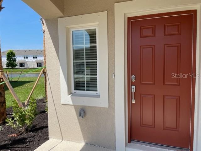 A red front door and a window are visible on the exterior of a house — 5764 HAVEN TERRACE, NOKOMIS, FL