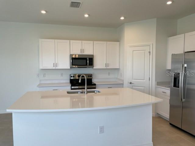 A kitchen features white cabinets, stainless steel appliances, and a large white quartz island — 5764 HAVEN TERRACE, NOKOMIS, FL
