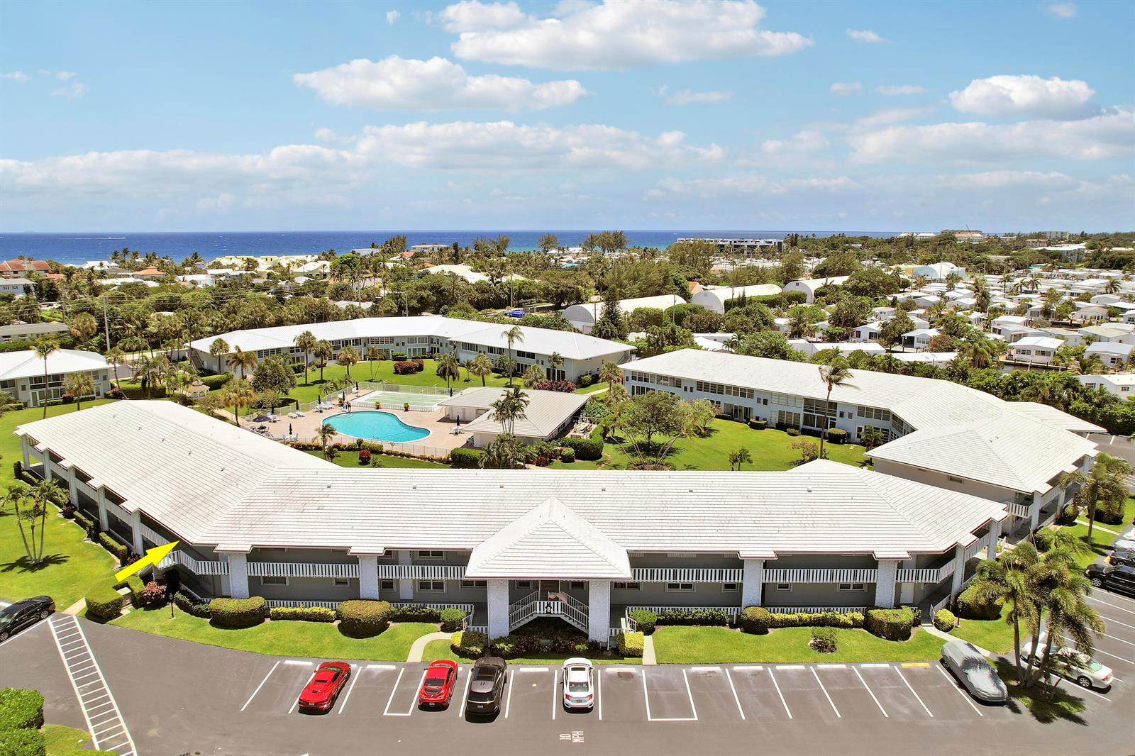 An aerial view shows a multi-story apartment complex with a central pool and parking lot — 5540 N Ocean Boulevard # 206, Ocean Ridge FL 33435, OCEAN RIDGE, FL