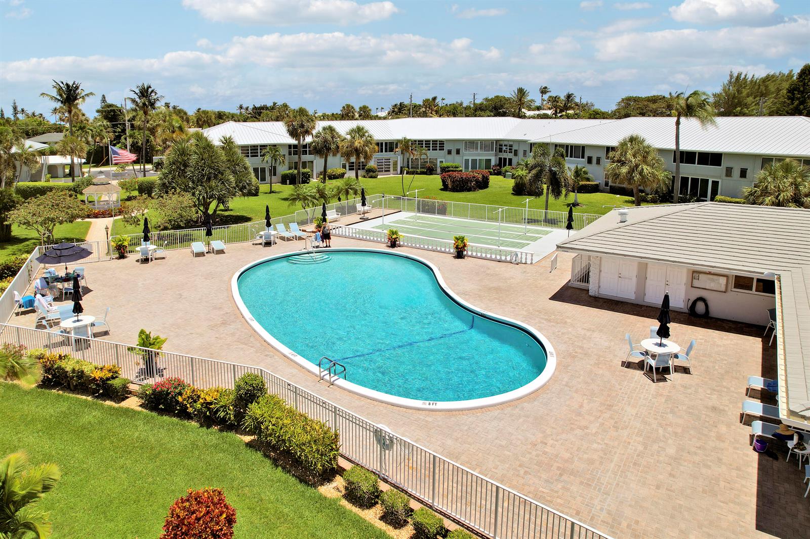 An aerial view of a swimming pool, tennis court, and surrounding apartment buildings — 5540 N Ocean Boulevard # 206, Ocean Ridge FL 33435, OCEAN RIDGE, FL