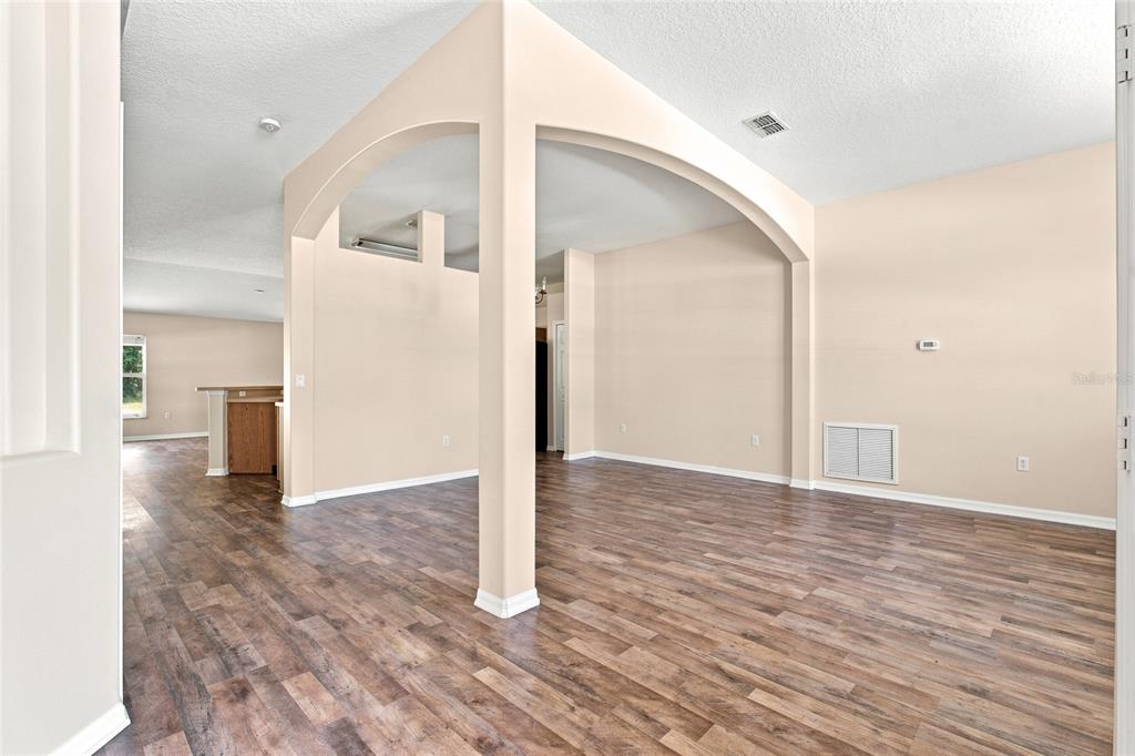 An interior view of a living area featuring arched architectural details and wood-look flooring — 103 WOODSIDE DRIVE, PALM COAST, FL