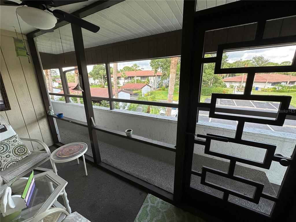 A screened-in balcony features a ceiling fan, outdoor furniture, and views of a parking lot — 3500 EL CONQUISTADOR PARKWAY UNIT 314, BRADENTON, FL