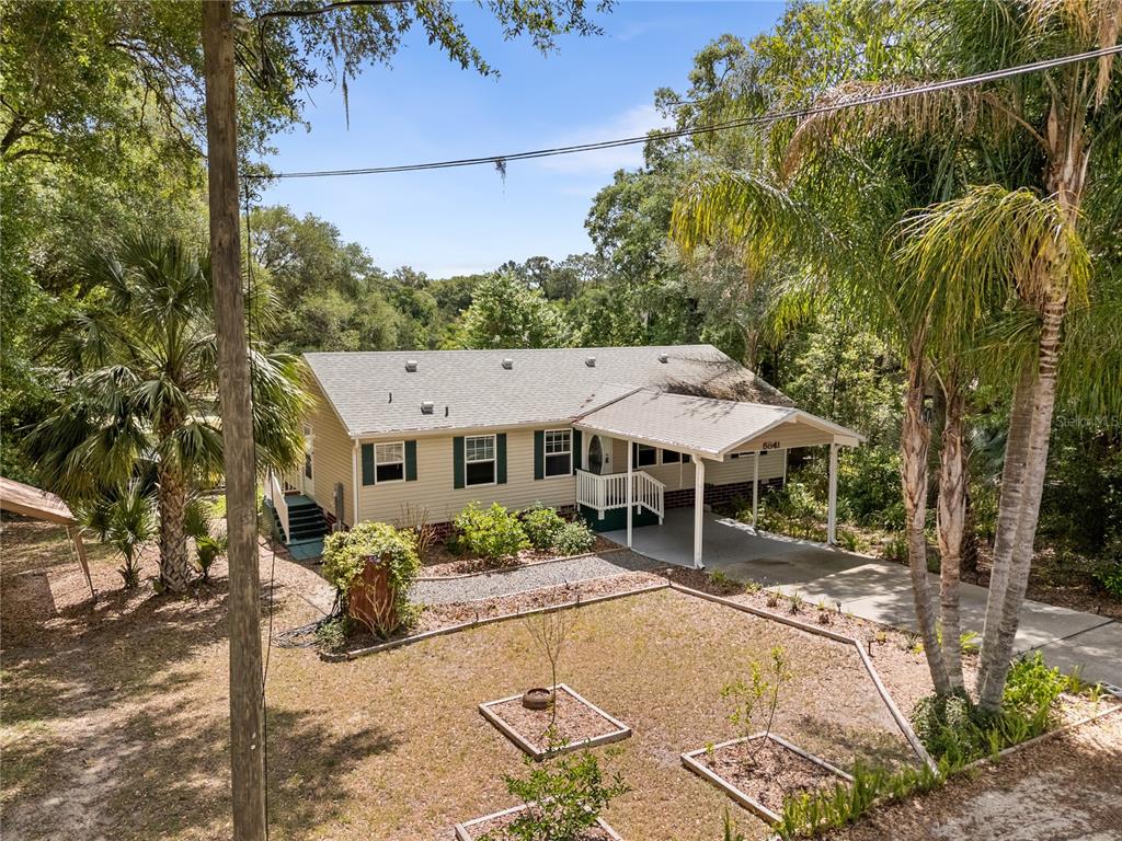 An elevated view of a single-story house with a carport and a landscaped front yard — 5841 SE 164TH AVENUE, OCKLAWAHA, FL