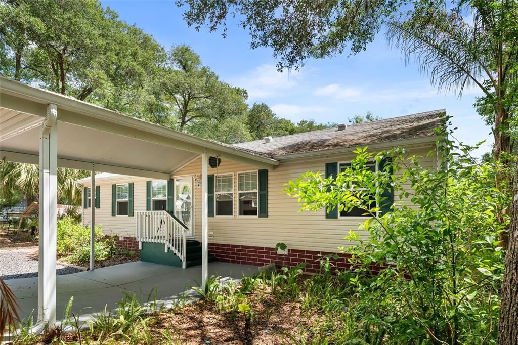 A single-story house with beige siding, a brick base, and a covered carport entrance — 5841 SE 164TH AVENUE, OCKLAWAHA, FL