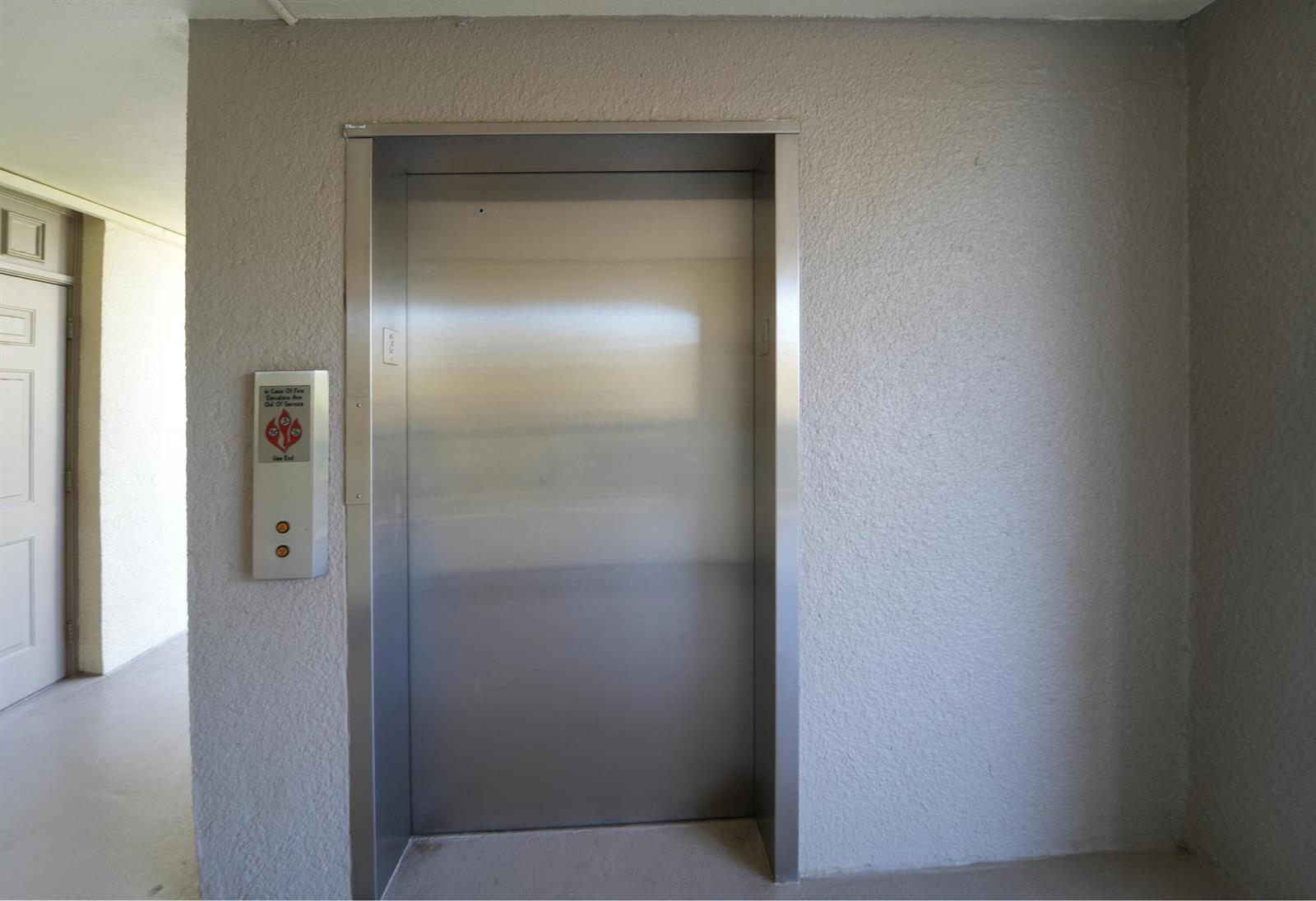 A stainless steel elevator door is set into a textured beige wall in a hallway — 1605 S Us Highway 1, Jupiter FL 33477, JUPITER, FL