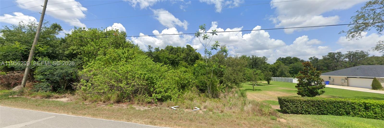 A vacant, overgrown lot sits next to a house with a manicured lawn — 1701 N GASTER RD, Avon Park FL 33825, AVON PARK, FL