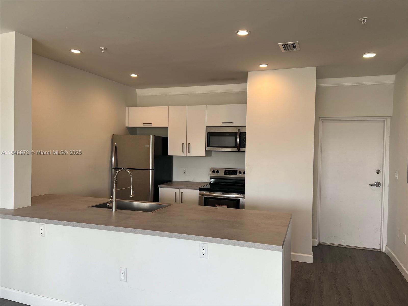 A kitchen features white cabinets, stainless steel appliances, and a gray countertop island — 2311 NW 22nd Ave # 207, Miami FL 33142, MIAMI, FL