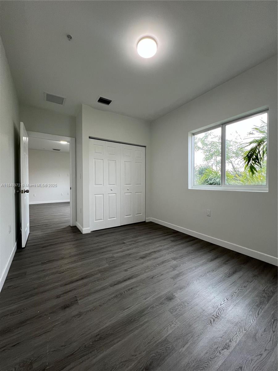 This bedroom features gray wood-look flooring, white walls, a closet, and a single window — 2311 NW 22nd Ave # 207, Miami FL 33142, MIAMI, FL