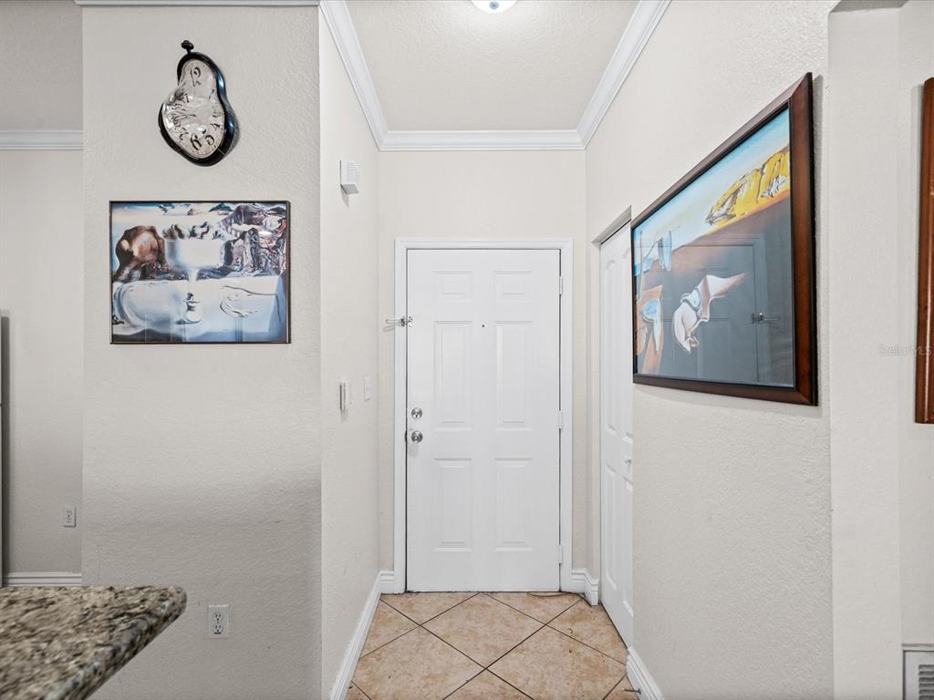 A tiled entryway features a white front door, a closet, and surrealist wall art — 2731 VIA CAPRI UNIT 925, CLEARWATER, FL