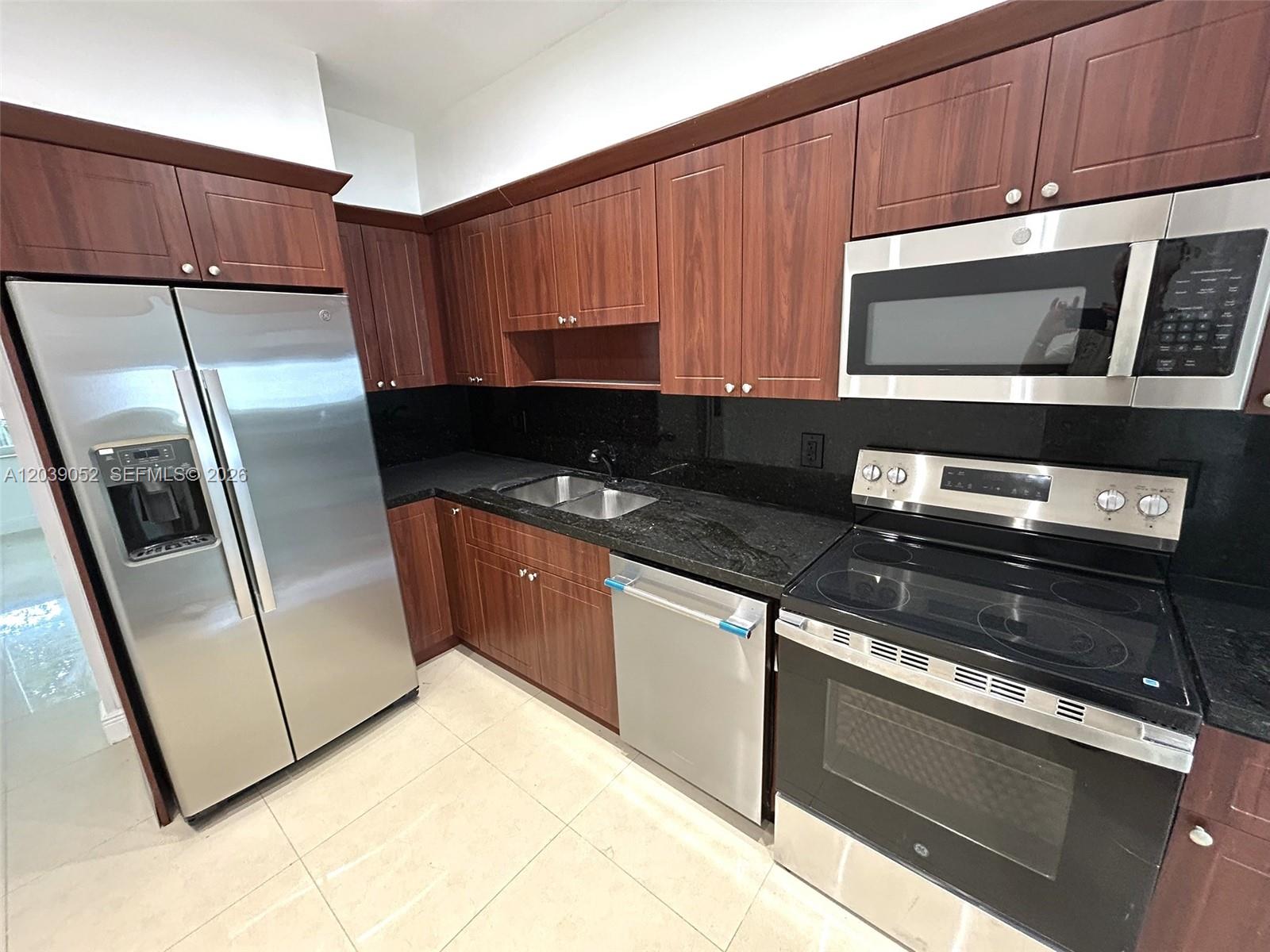 A kitchen features dark wood cabinets, black granite countertops, and stainless steel appliances — 1530 NE 110th Ter, Miami FL 33161, MIAMI, FL
