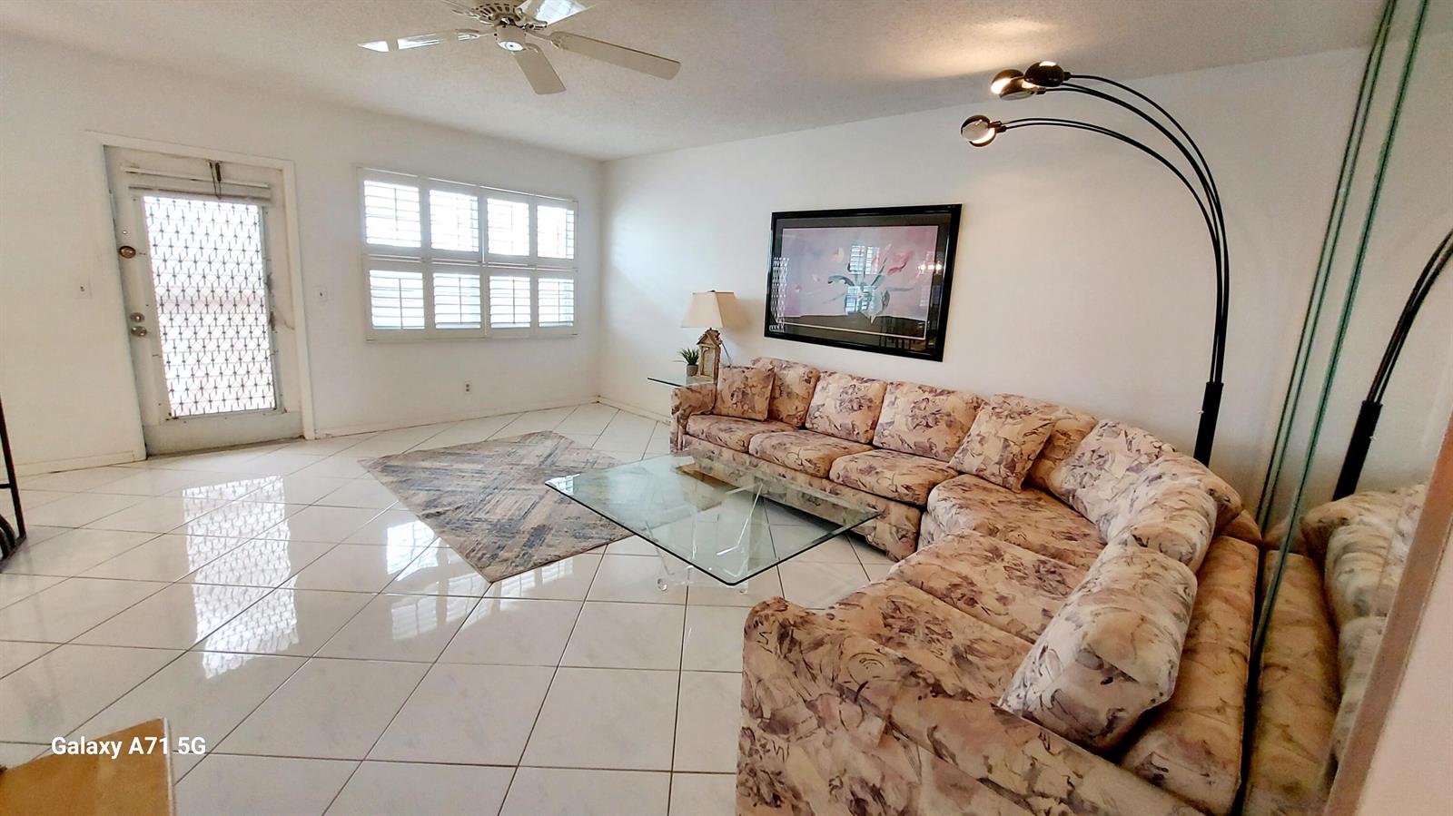 A living room features white tile floors, a floral sectional sofa, and a glass coffee table — 4079 Cornwall D # 4079, Boca Raton FL 33434, BOCA RATON, FL