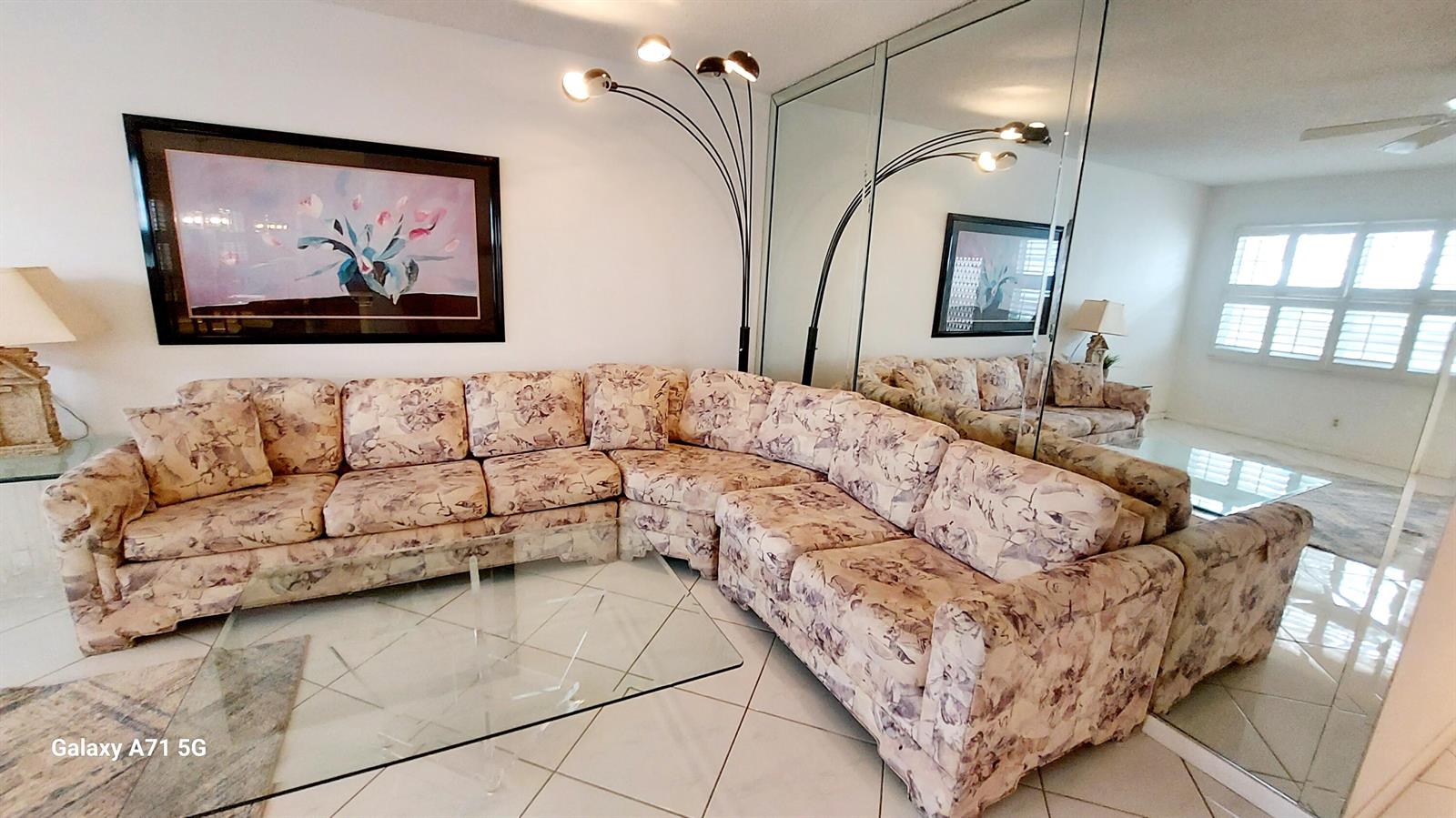 A living room features a floral sectional sofa, a glass coffee table, and mirrored walls — 4079 Cornwall D # 4079, Boca Raton FL 33434, BOCA RATON, FL