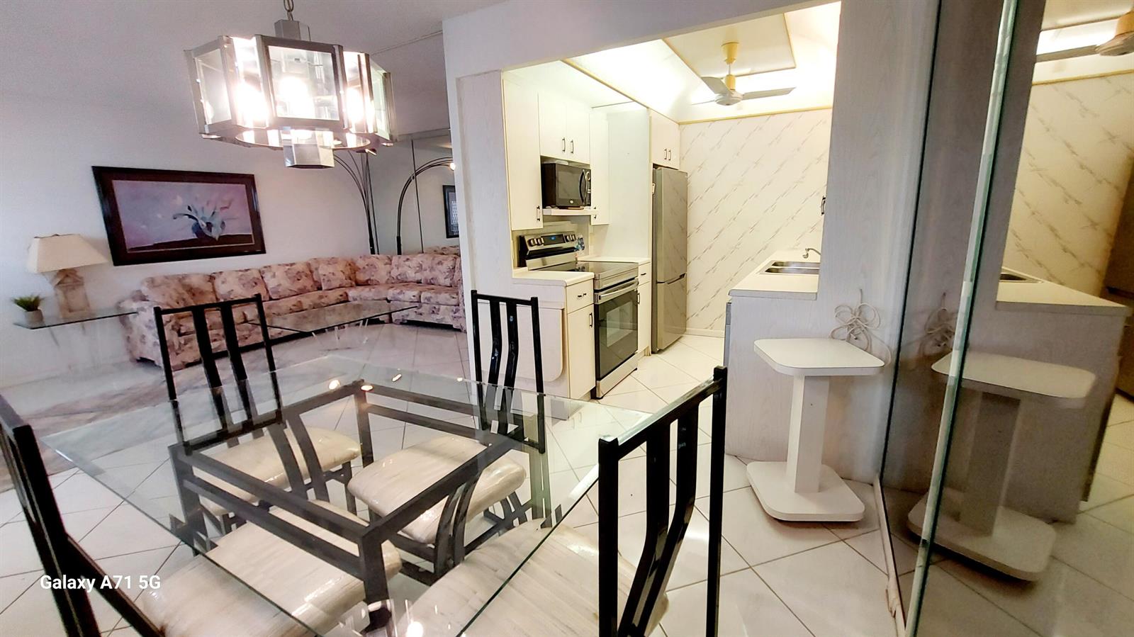 A dining area with a glass table and chairs sits adjacent to a galley kitchen — 4079 Cornwall D # 4079, Boca Raton FL 33434, BOCA RATON, FL