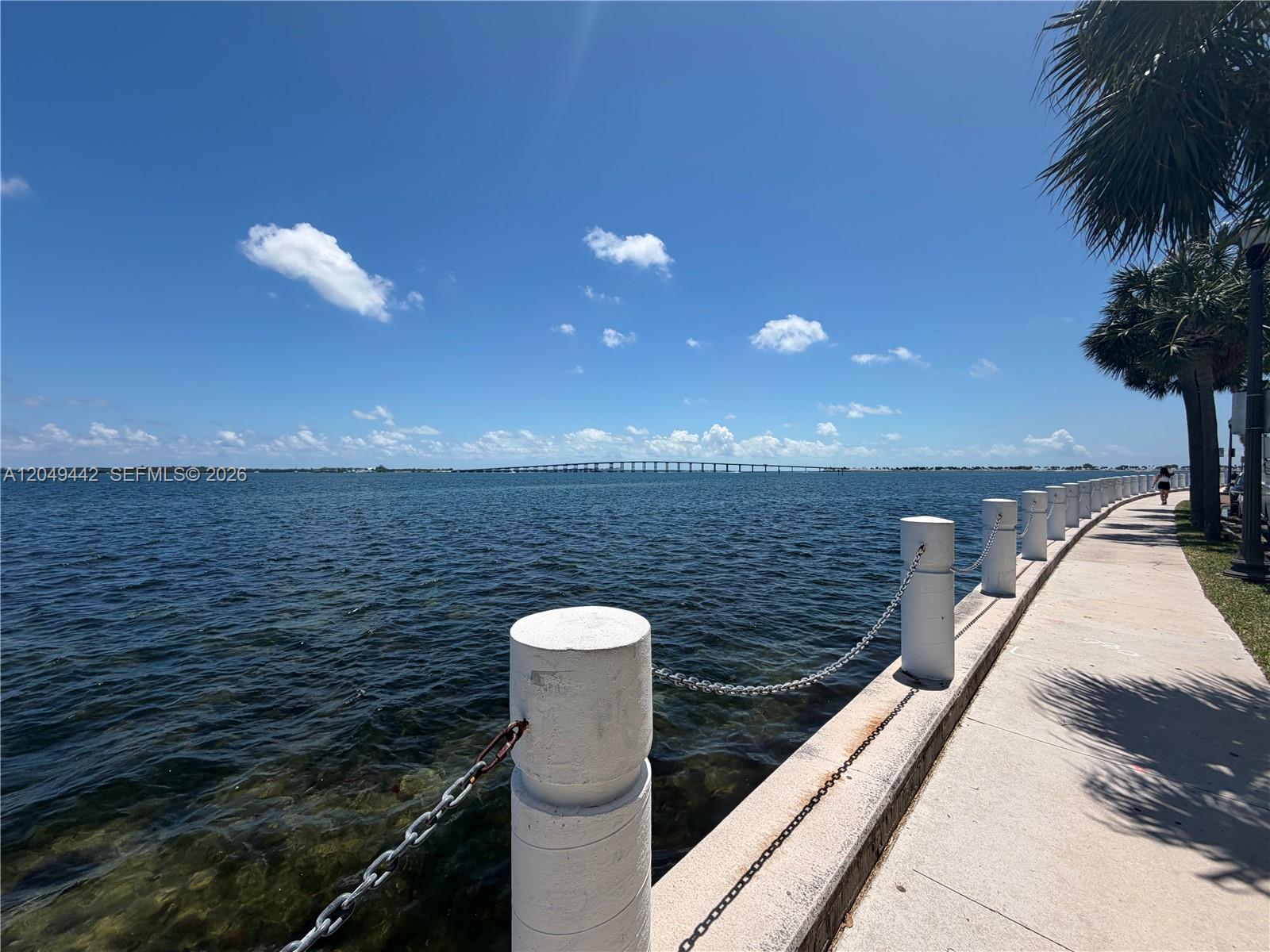 A concrete walkway with white bollards and chains runs alongside a body of water — 1420 Brickell Bay Dr # 1005C, Miami FL 33131, MIAMI, FL