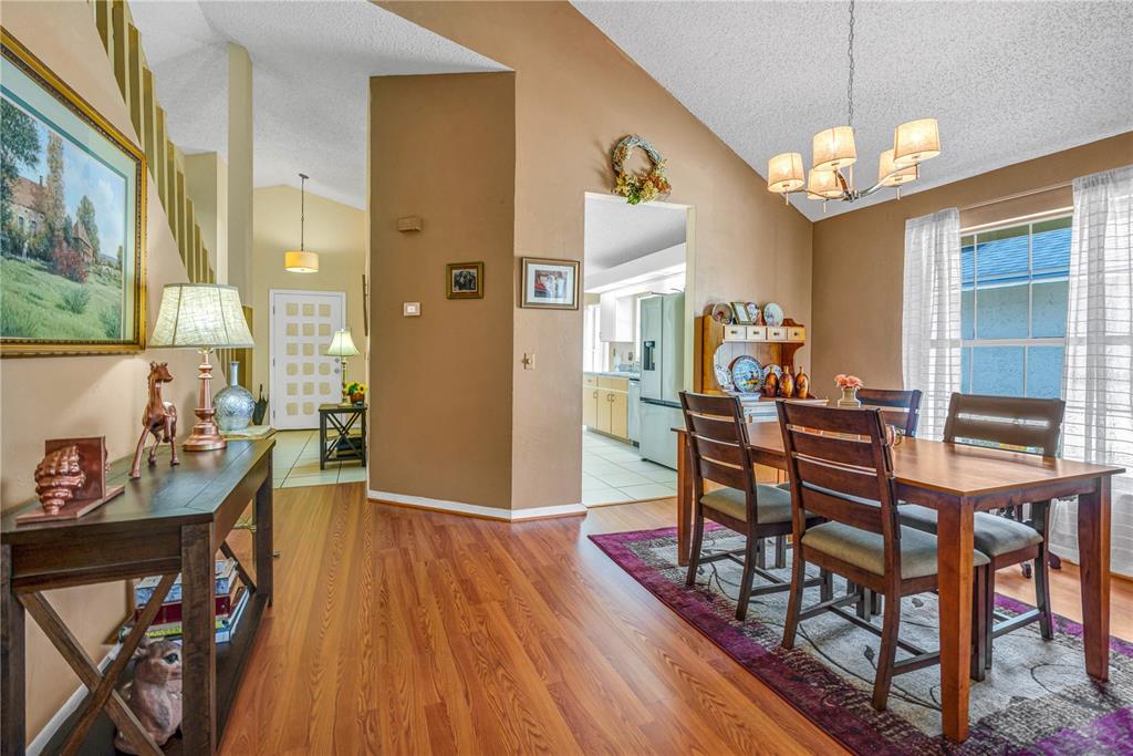 A dining room with wood floors and a table set leads to a kitchen area — 524 CROOKED STICK DRIVE, DAYTONA BEACH, FL