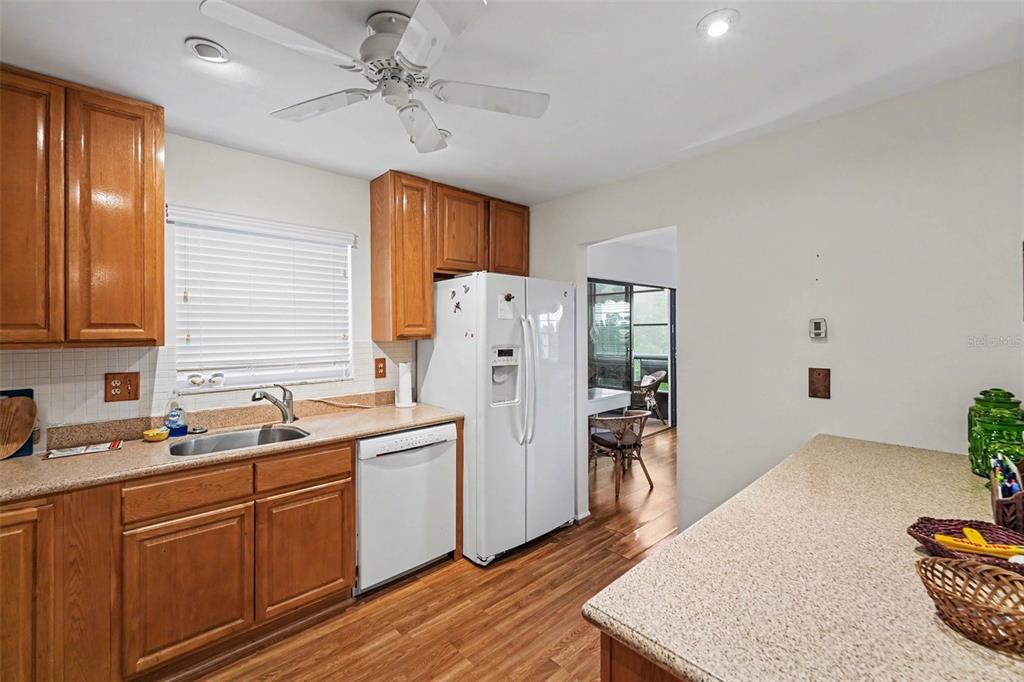 A kitchen with wood cabinets, laminate countertops, a white refrigerator, and wood-look flooring — 5970 80TH ST N UNIT 301, ST PETERSBURG, FL