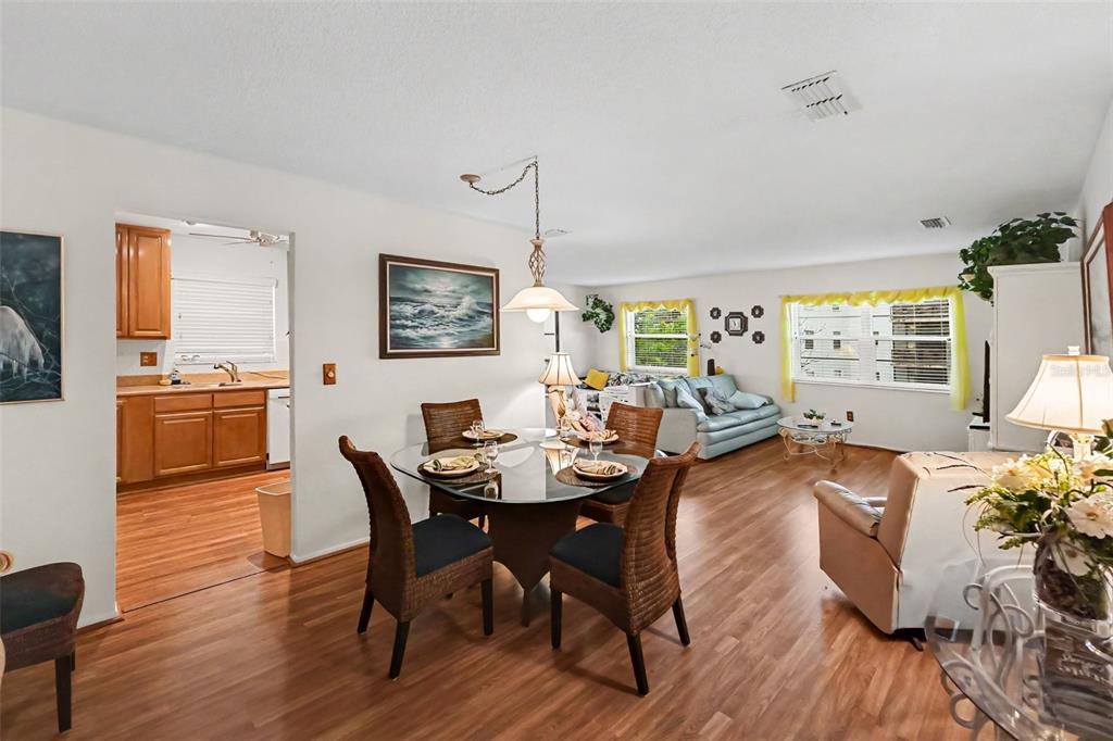 A dining area with a glass table and wicker chairs opens into a living room — 5970 80TH ST N UNIT 301, ST PETERSBURG, FL