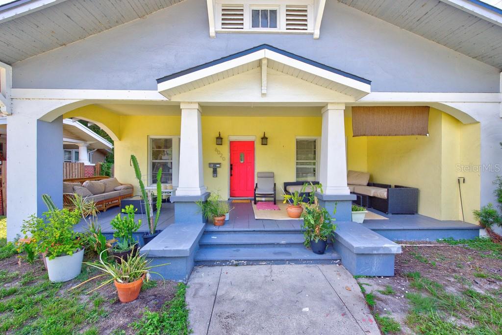 A front view of a house with a yellow porch, blue trim, and a red door — 6020 N FLORA VISTA AVENUE, TAMPA, FL