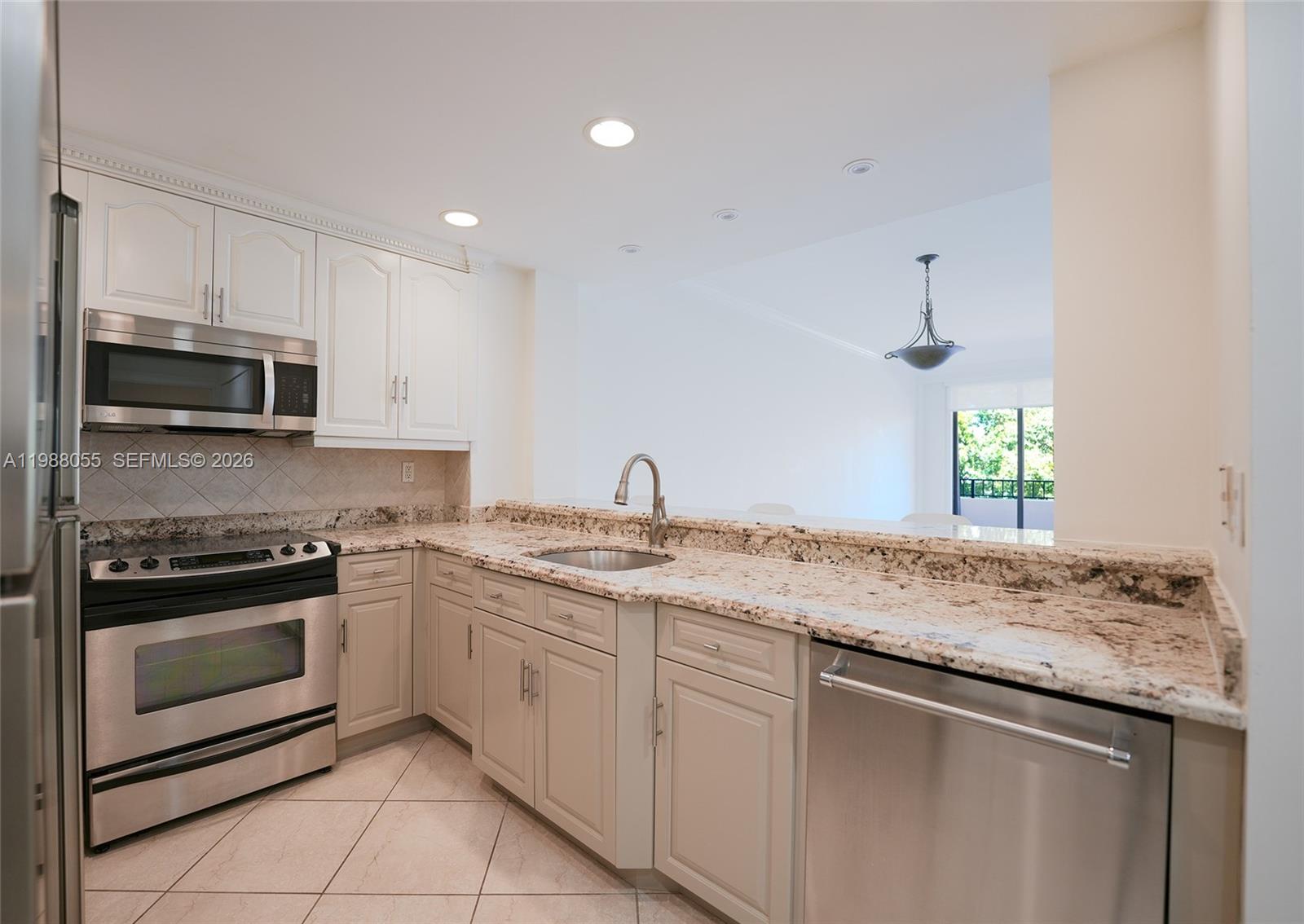 A kitchen features white cabinets, granite countertops, stainless steel appliances, and a pass-through window — 151 Crandon Blvd # 320, Key Biscayne FL 33149, KEY BISCAYNE, FL