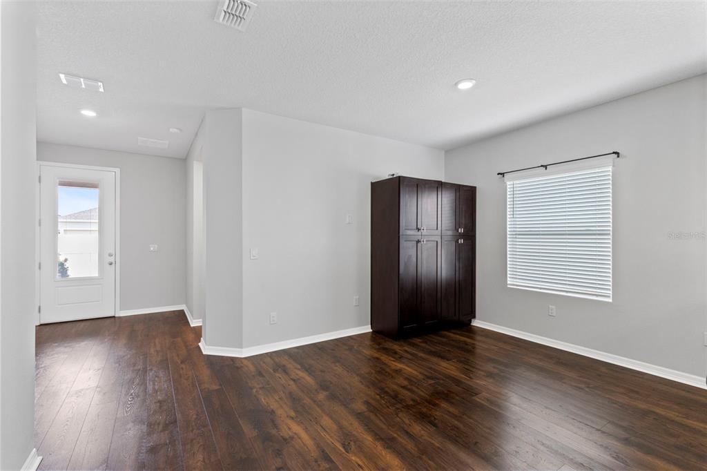 A room with dark wood flooring, light gray walls, a window, and a dark cabinet — 2937 DEERBERRY LANE, CLERMONT, FL