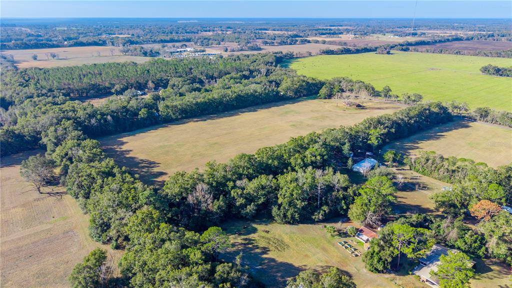 An aerial view shows a large grassy field surrounded by dense trees and rural property — 0000 SW 202 STREET, NEWBERRY, FL