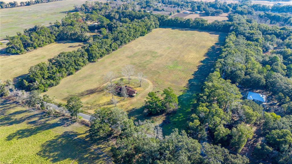 An aerial view shows a house situated on a large, grassy lot surrounded by trees — 0000 SW 202 STREET, NEWBERRY, FL