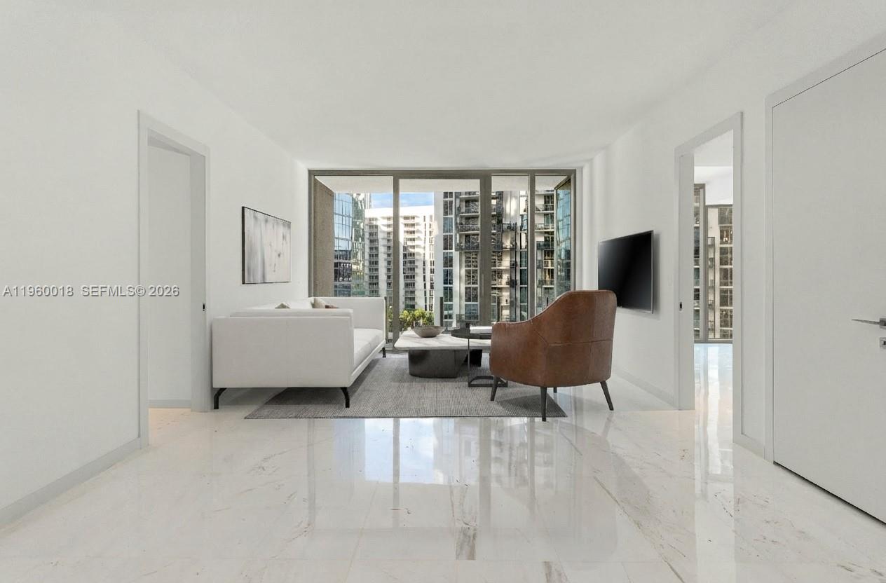 A modern living room features white marble floors, a white sofa, and a brown chair — 300 BISCAYNE BLVD WAY # 2009, Miami FL 33131, MIAMI, FL