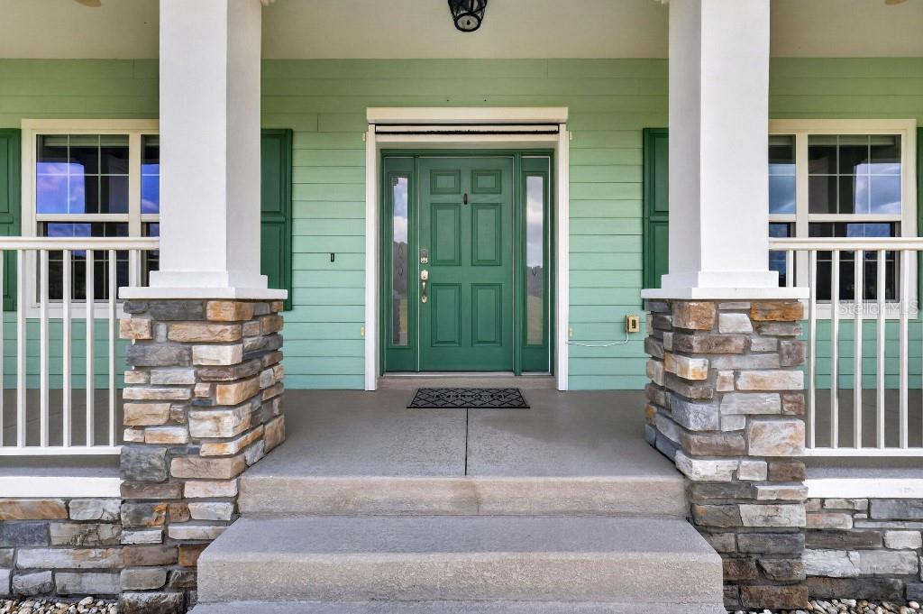 A front porch with stone pillars, a green door, and light green horizontal siding — 2556 NE 120TH STREET, ANTHONY, FL