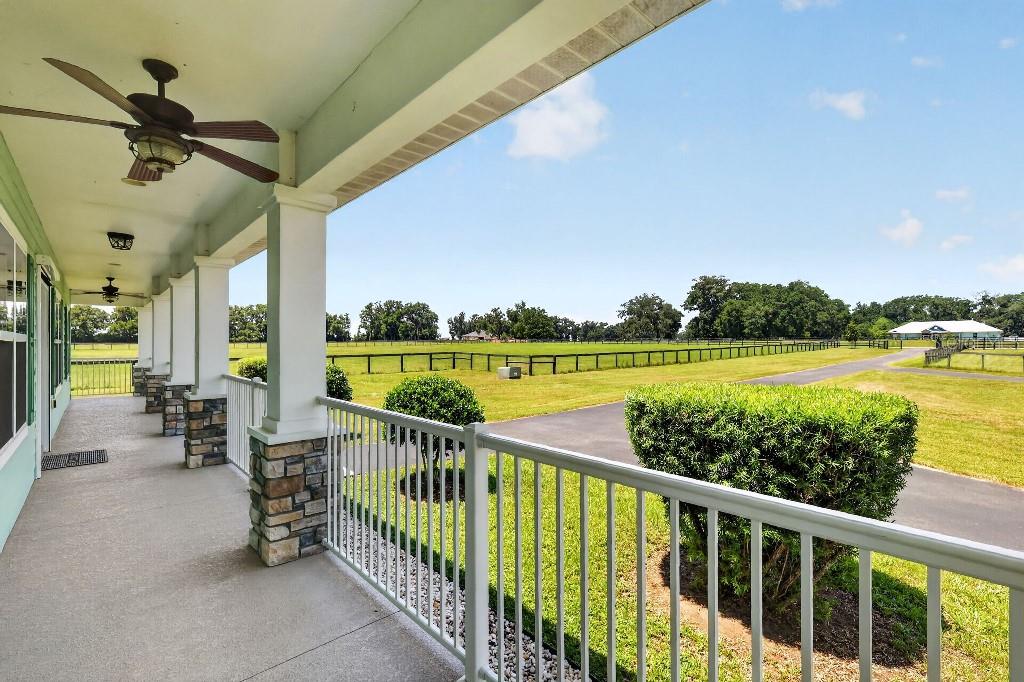 A covered porch with stone-based columns overlooks a large grassy field and a paved driveway — 2556 NE 120TH STREET, ANTHONY, FL