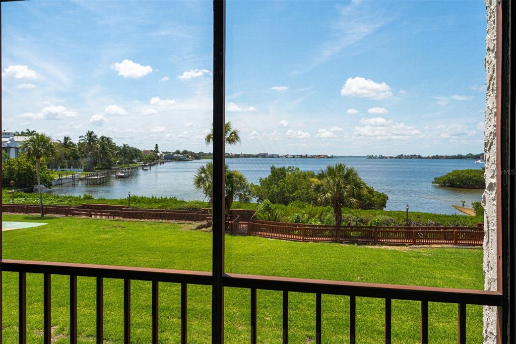 A view of a grassy lawn and a bay from a screened-in porch — 1608 STICKNEY POINT ROAD UNIT 1608-204, SARASOTA, FL