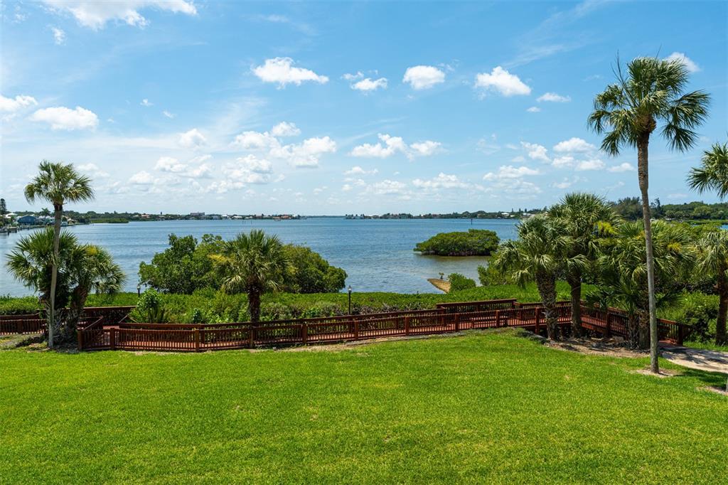 A grassy lawn overlooks a bay with palm trees and a wooden boardwalk — 1608 STICKNEY POINT ROAD UNIT 1608-204, SARASOTA, FL
