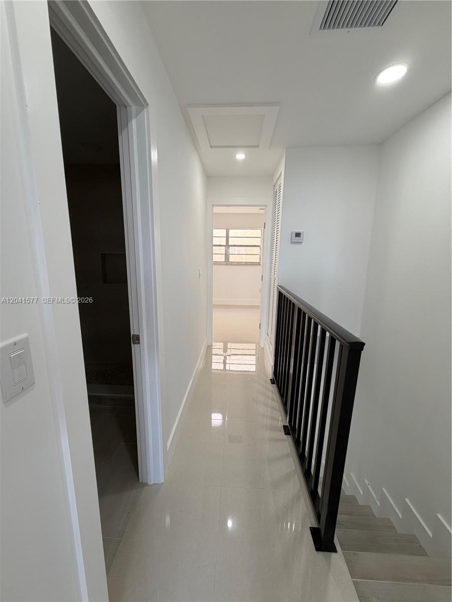 A bright hallway features white walls, tile flooring, and a black metal stair railing — 1551 W Okeechobee Rd # 3, Hialeah FL 33010, HIALEAH, FL