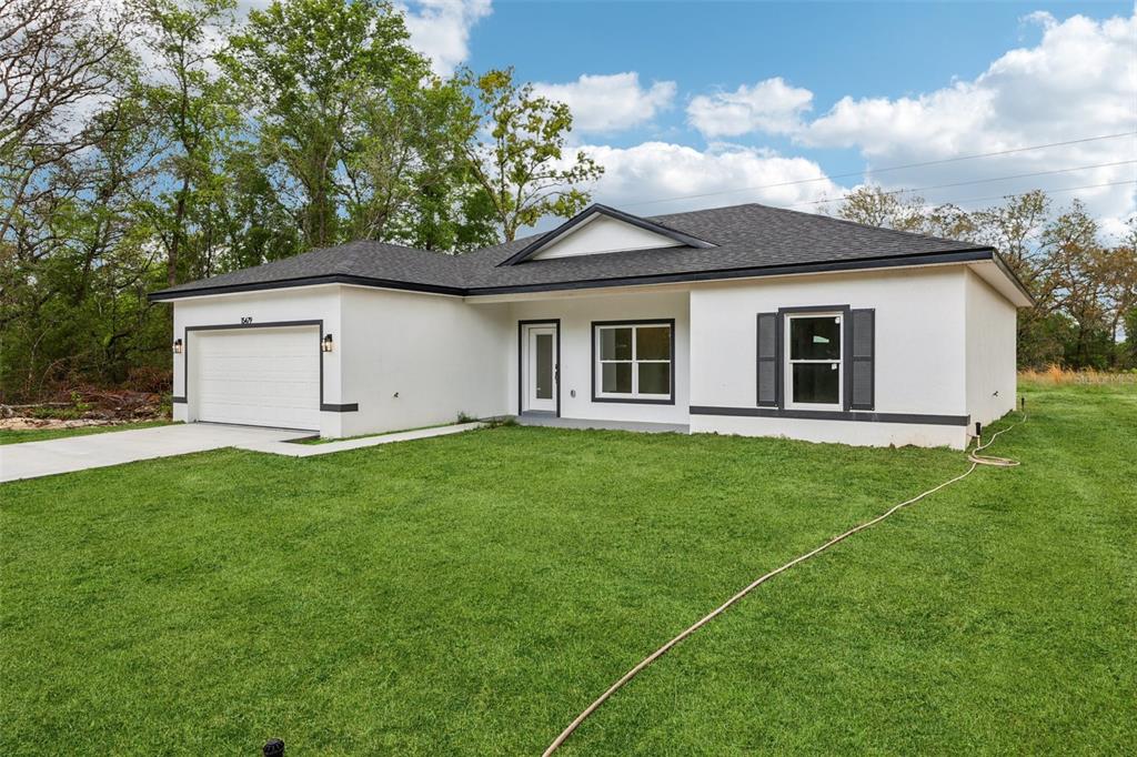 A white exterior wall features a front door with a window and a nearby window — 15479 SE 115 PLACE ROAD, OCKLAWAHA, FL