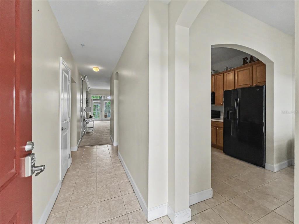 A tiled entryway leads to a hallway and an arched opening into a kitchen — 1411 CELEBRATION AVENUE UNIT 309, CELEBRATION, FL