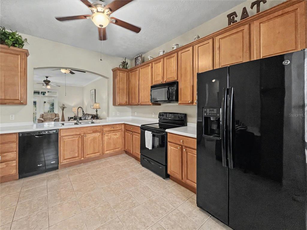 A kitchen with light wood cabinets, black appliances, and tile flooring — 1411 CELEBRATION AVENUE UNIT 309, CELEBRATION, FL