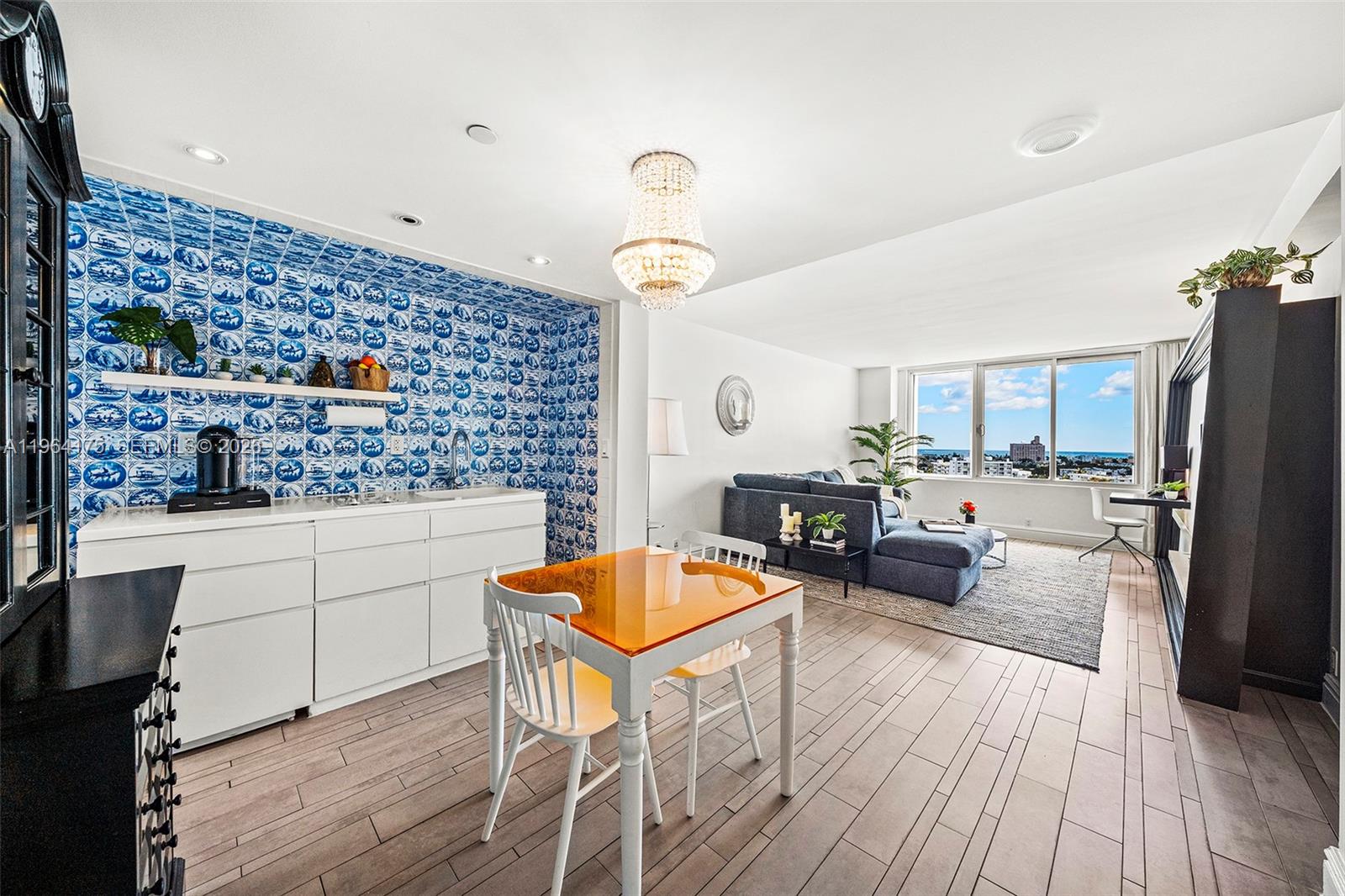 A living room and kitchen area features a blue-tiled wall, chandelier, and ocean view windows — 1100 West Ave # 1123, Miami Beach FL 33139, MIAMI BEACH, FL