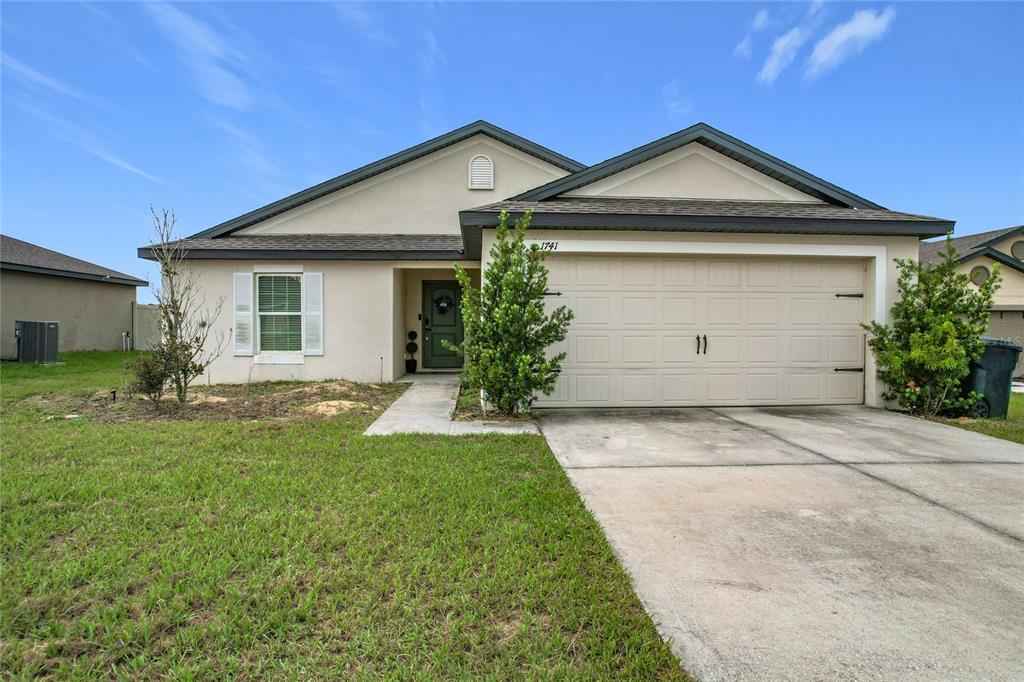 A single-story house with a beige stucco exterior, a two-car garage, and a front walkway — 1741 CANAAN LOOP, DUNDEE, FL