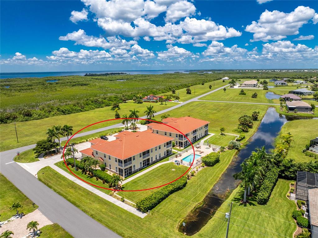 An aerial view shows a multi-story residential building with a red tile roof and pool — 17210 ACAPULCO ROAD UNIT 221, PUNTA GORDA, FL