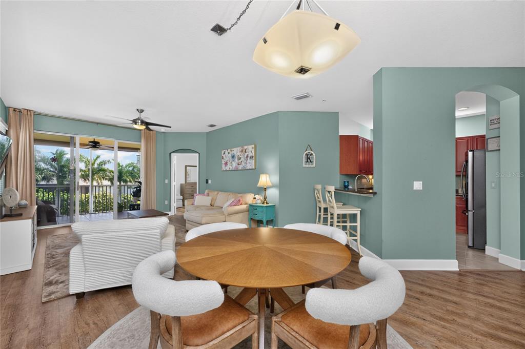 A dining area with a round table sits in front of a living room and kitchen — 17210 ACAPULCO ROAD UNIT 221, PUNTA GORDA, FL