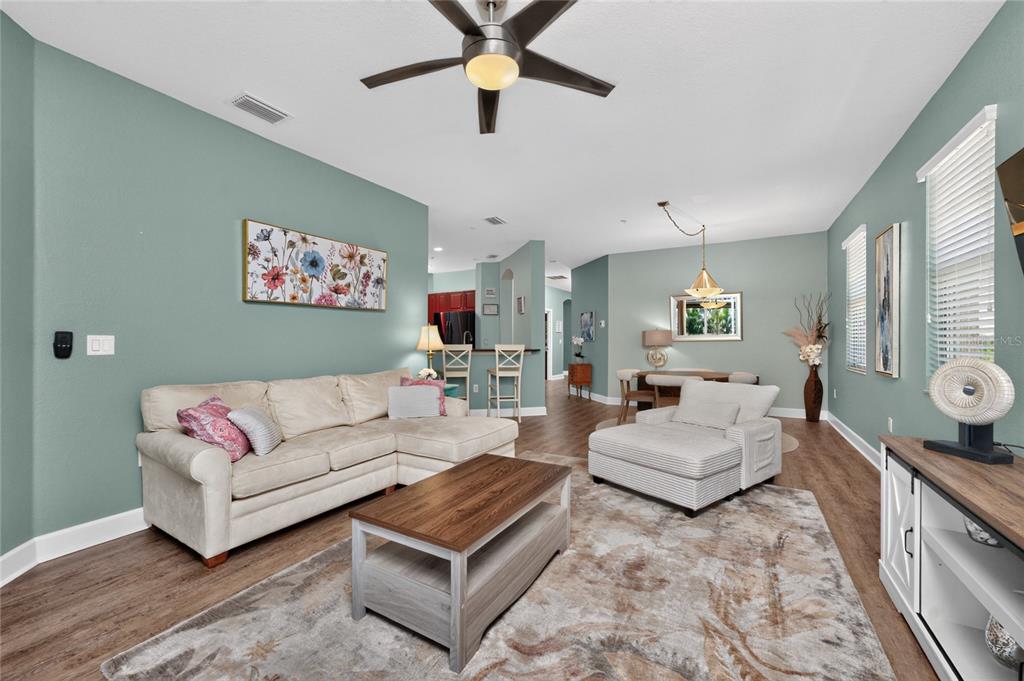 A living room with a sectional sofa, coffee table, and dining area on wood floors — 17210 ACAPULCO ROAD UNIT 221, PUNTA GORDA, FL