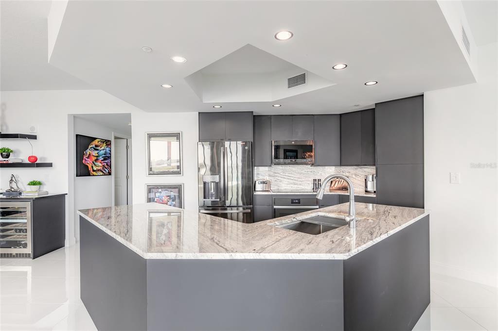 A modern kitchen features dark gray cabinetry, a large granite island, and stainless steel appliances — 241 RIVERSIDE DRIVE UNIT 701, HOLLY HILL, FL