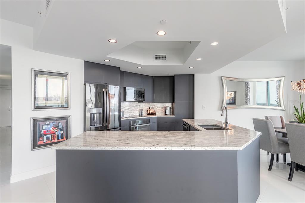 A modern kitchen features dark gray cabinetry, granite countertops, and a central island — 241 RIVERSIDE DRIVE UNIT 701, HOLLY HILL, FL